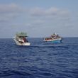De migrantenboot met links een vissersboot uit Gozo
