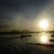 Een rivieraak vaart over het stille water tegen het zonlicht in naar het oosten