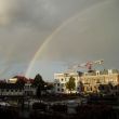 Onweer trekt weg, de zon keert terug met regenboog. Achtergrond: bouwkraan app<span class=