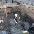 Opgraving site Bluebandhuis, 2e dag. Links wordt een fundatiebalk vrijgemaakt