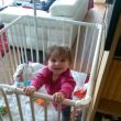 Lina-Mae (7,5 maanden) staat zegevierend rechtop in de box.