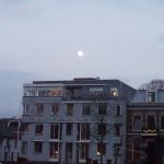 21 september. Een wazige ge bijna volle maan boven de huizen aan de Kriekenmarkt.