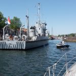 Hellevoetsluis. Een oud (houten) marineschip vaart langs, op weg naar de museumhaven achterin.