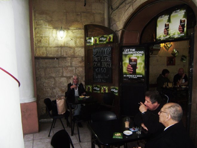 Onder de arcaden van een bruine kroeg in St Julians drinken we een glas wijn