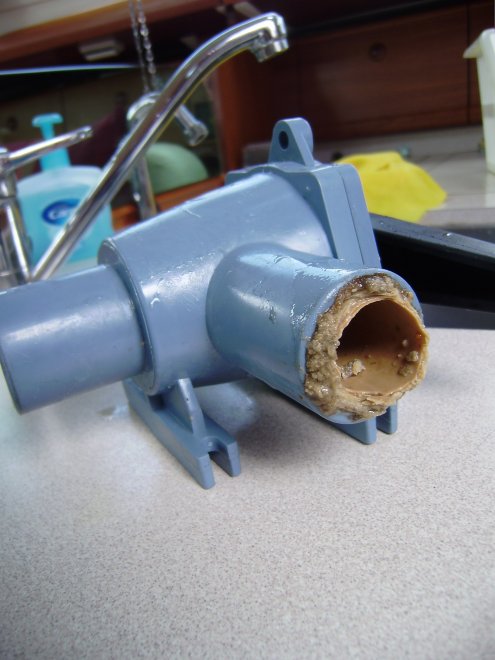 De afvoerslangen van het toilet zitten vol aderverkalking. Ook de driewegklep heeft een centimeterdikke kalklaag, waar een vieze prop toiletpapier (met de rest) vastzat