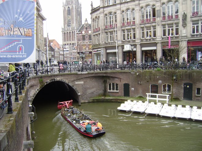 Boekhandel Selexyz Broese bij de Stadhuisbrug in Utrecht. Er vaart juist een boot met uit de gracht opgeviste fietsen voorbij