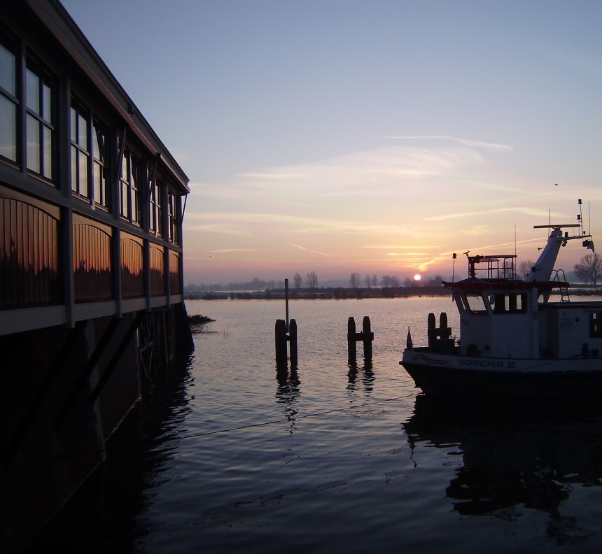 Zonsopgang Buiten de Waterpoort. Links de pui van restaurant `Merwezicht`, rechts de watertaxi Gorcum