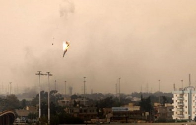 Neerstortend jachtvliegtuig boven de Libische stad Benghazi. De twee stipjes links van het toestel zou de piloot in zijn schietstoel met parachute kunnen zijn (foto AFP) Ironie, het toestel bleek van de opstandelingen zelf te zijn. De piloot kwam om