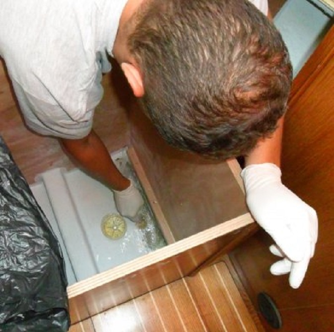 Kostas repareert met glasvezelmatjes en epoxy de zwakke plek onder het bed in de voorhut