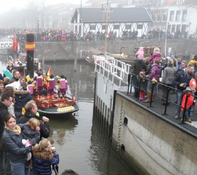 De stoomboot van Sinterklaas vaart de sluis uit. Linksonder zie je Tessa met Vajèn op de arm