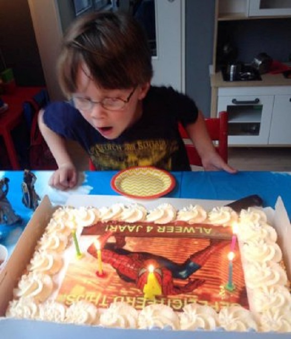 Kleinzoon Thijs (4) blaast de kaarsen op zijn verjaardagstaart uit