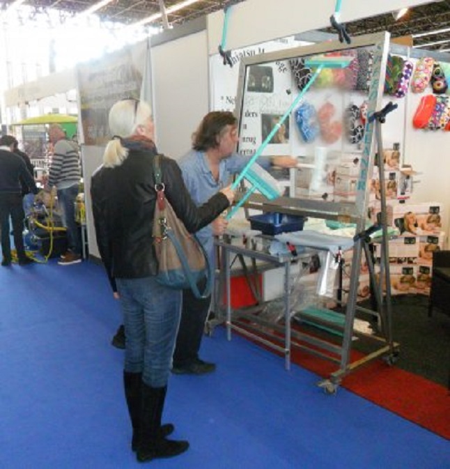 Een langharige standwerker demonstreert Ans de wondere waskracht van zijn nieuwe ramenlapper