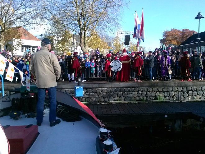 Lourens kijkt in Veghel op de voorplecht van 'Niets Zonder Gods Zegen' naar de Sint op de kade.