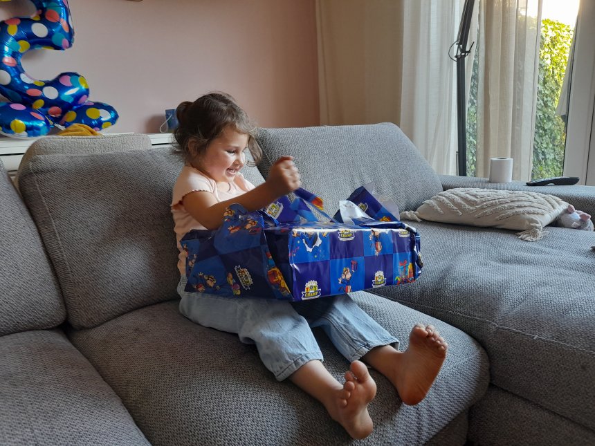 Jarige Noira pakt ons cadeautje uit.